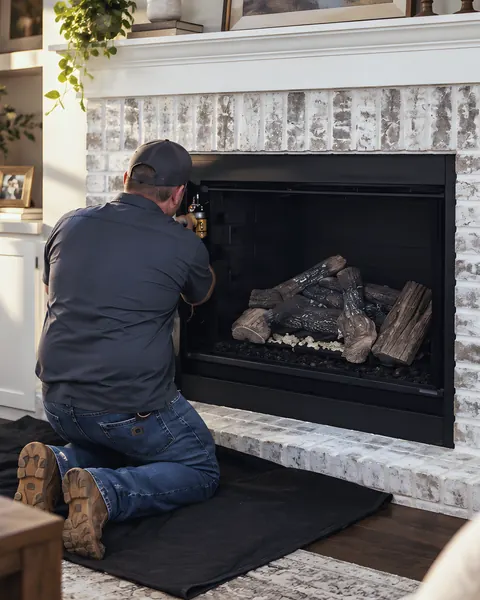 Uniformed technician servicing a gas fireplace: an AI-enhanced reconstruction of TDi Services’s own photograph.